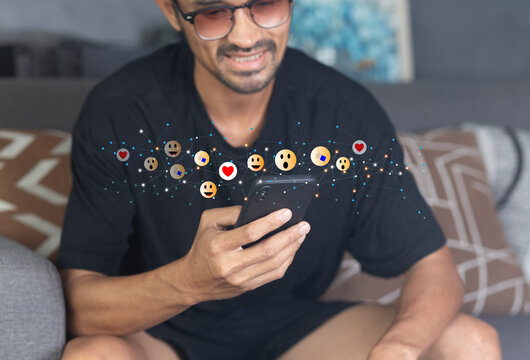 Social media concept with happy young man using smartphone with giving icon rating during watching live at home 
