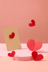 Front view of an empty podium decorated with paper card and red paper hearts on a sweet pink background. Blank space for display product. Minimalist concept for women’s day decoration