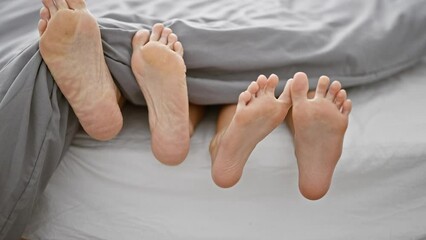 Mother and daughter lying together, comfortably moving their feet on a cozy bed in bedroom, sharing a relaxed morning in their home, deepening the bond of their relationship indoors