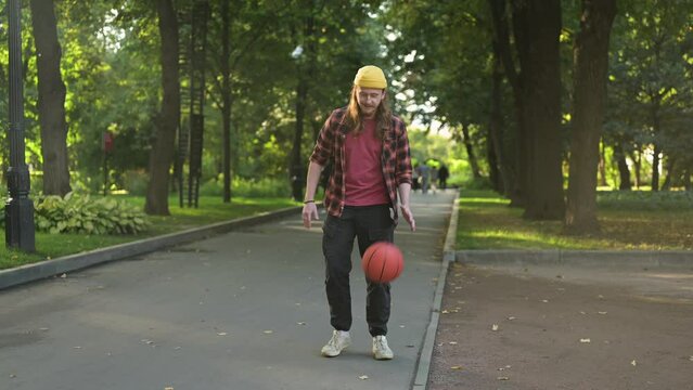 Young red-haired guy dunking a basketball in the park on a summer evening - Powered by Adobe