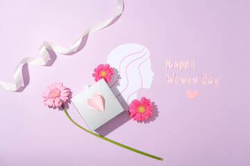 Flat lay of a ring box featured with some flowers and paper and a white ribbon. Paper cut in...
