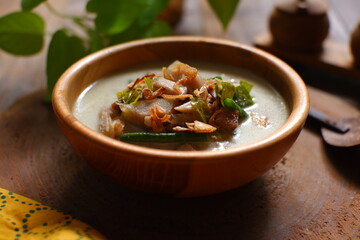 a bowl of sayur nangka muda against wooden background 