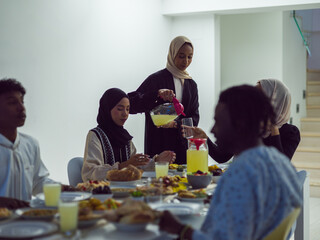 Fototapeta na wymiar A diverse Islamic family gathers for iftar, joyfully breaking their fast together during Ramadan, with a Muslim woman in a beautiful hijab gracefully pouring water to mark the end of their fast