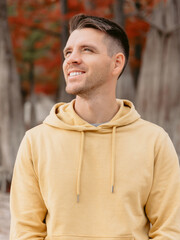 Obraz premium Handsome man in autumnal park. Portrait of smiling caucasian man in yellow hoodies