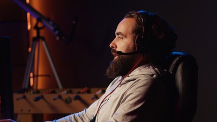 Man having fun with his friends playing videogames, chatting online using headphones microphone. Gamer using computer with powerful graphics to enjoy multiplayer experience with teammates