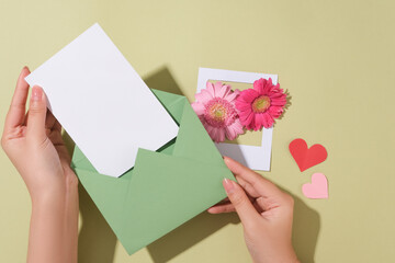 The model prepares to put the white card with copy space in the envelope. A paper picture frame...