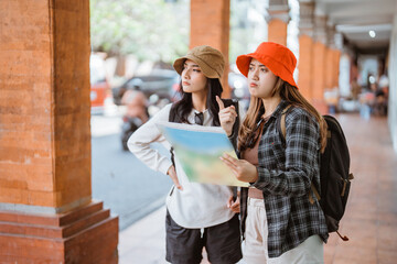 two Asian tourists look at a map on their way to a tourist destination