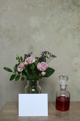 glass vase, flowers and blank card on table