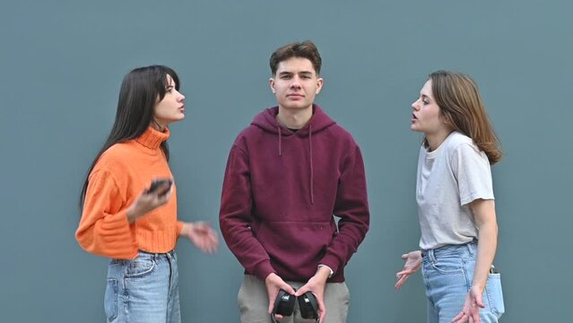 A young guy puts on headphones, tired of listening to the screams of his girlfriends. Two young women scream at a guy who endures it and then puts on headphones to drown out the screams.