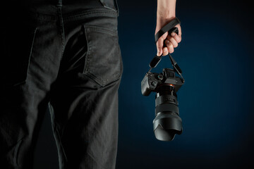 photographer holding a mirrorless camera dangling on the neck strap studio shot - Powered by Adobe