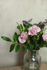 bouquet of pink carnations in a vase on a wooden table. copy space.