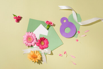 Top view of colorful flowers displayed with an envelope containing a card inside. White ribbon and two purple circles arranged to form the number 8 featured