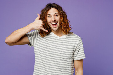 Young smiling cheerful man he wears grey striped t-shirt casual clothes doing phone gesture like says call me back isolated on plain pastel light purple background studio portrait. Lifestyle concept.