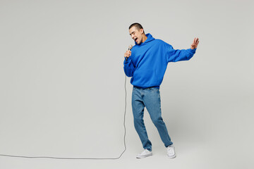 Full body singer young middle eastern man wear blue hoody casual clothes sing song in microphone at...