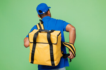 Back rear view professional delivery guy employee man wear blue cap t-shirt uniform workwear yellow thermal food bag work as dealer courier backpack isolated on plain green background Service concept