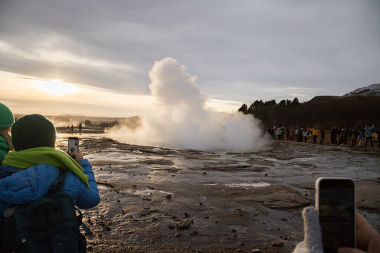 tourists observing and capturing the eruption of the Strokkur geyser, Geysir geothermal field, Iceland