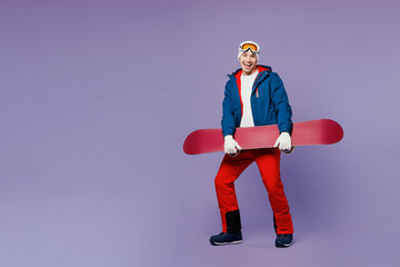 Full body cheerful smiling man he wear blue windbreaker jacket ski goggles mask hat hold snowboard...