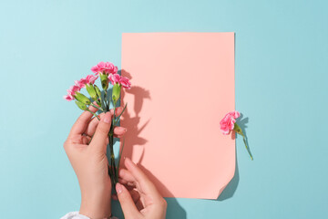 Beautiful female hand model holding a bouquet of pink flowers. Blank paper in pink color featured...