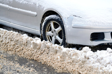 Snow pile after plowing street blocking car at roadside. Problem with plowing snow in the city due...