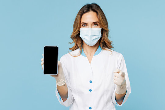 Female doctor woman wear white medical gown suit work in hospital clinic office hold mobile cell phone point finger camera on you isolated on plain blue background studio Health care medicine concept