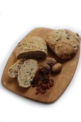 Homemade sliced Pan co' Santi from Tuscany (Italy) on wooden cutting board on white. Traditional sweet bread with raisins, almonds, walnuts and aniseed and Vinsanto