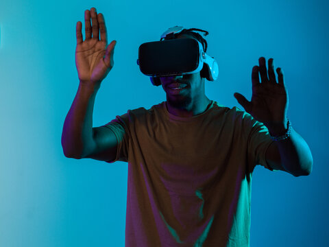 Immersed in a digital realm, an African American man navigates the virtual landscape with a VR goggles, using tactile gestures to interact with virtual objects, showcasing a harmonious blend of