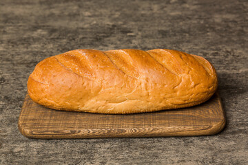 Freshly baked bread on cutting board against white wooden background. perspective view bread with copy space