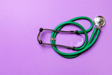 Top view of green medical stethoscope on colorful background with copy space. Medicine equipment concept