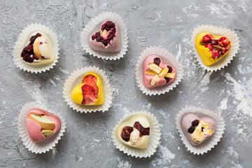 chocolate sweets in the form of a heart with fruits and nuts on a colored background. top view with space for text, holiday concept