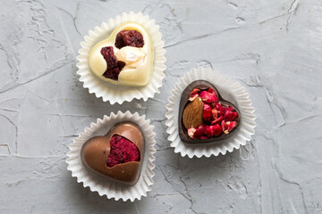 chocolate sweets in the form of a heart with fruits and nuts on a colored background. top view with space for text, holiday concept