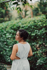 Fototapeta premium Portrait of Asian Woman in a white dress near the lake in the forest