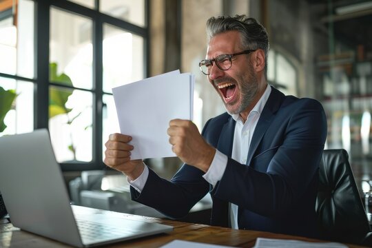 Happy Mature Older Business Man Ceo Wearing Suit Celebrating Success At Work In Office Holding Papers Looking At Laptop Rejoicing Company Growth, Goals Achievement Good Results Screaming,Generative AI