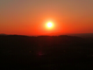 Ein roter Himmel, schwarze Silhouetten und die aufsteigende Sonne.