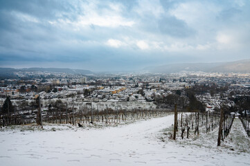Fototapeta na wymiar Vineyard with view of the ancient roman city of Trier covered in snow, Moselle Valley in Germany, winter landscape in rhineland palatine 