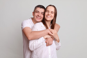 Beautiful wife lady and handsome husband guy with toothy smiles couple hugging being in good mood perfect pair hold in love wearing casual shirts isolated over gray background