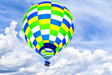Colorful hot air balloon flying over blue sky with white clouds	