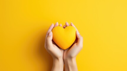 Female hands on a yellow background holding a yellow heart. The concept of donations and family insurance, World Heart Day. Valentine's Day. - obrazy, fototapety, plakaty