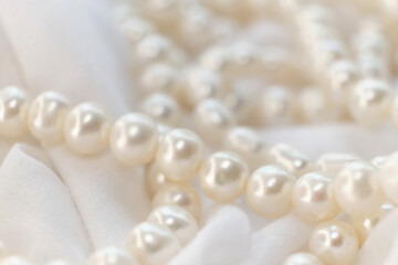 Fototapeta na wymiar A string of natural pearls lay elegantly on a pale canvas, their soft focus creating a dreamy atmosphere. This image evokes a return to natural beauty amidst the modern era's harsh synthetic