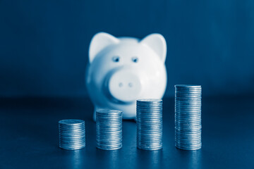 Piggy bank and stacks of coins for finance and banking concept with blue color filter. 