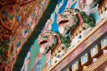 Snow lions with turquoise manes bas reliefs on wall above entrance to Buddhist temple, decorative...