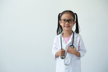 Smiling girl wearing glasses wearing a doctor's coat in medical practice standing holding a medical stethoscope Happy smile, learning plan on white background. Career concept. Plan for the future.