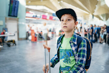 cute caucasian boy in airport with backpack and suitcase. Travelling concept