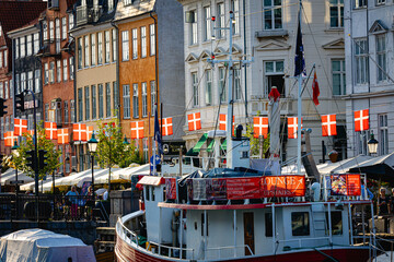 Nyhavn city canal in copenhagen with flags and boats at sunset