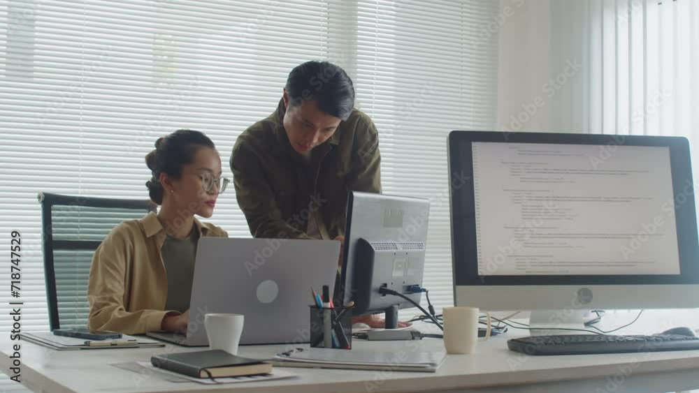Wall mural medium long shot of two asian coders analyzing idea while developing new app for users using compute