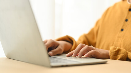 Cropped shot young woman wearing casual clothes working on laptop at home