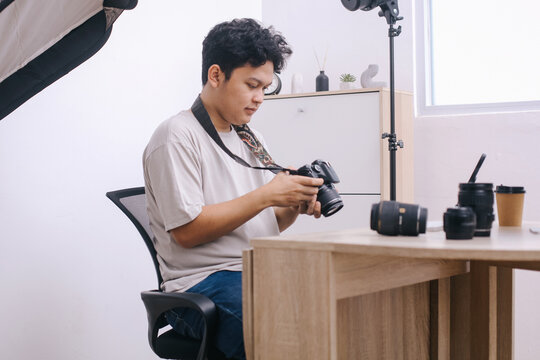 Photographer sitting and press button of professional camera to review shoot or setting camera at home office studio.