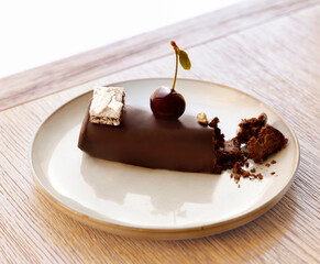 dark chocolate mousse cake with cherry and fistic on a plate in cafe. french pastry dessert. cake crumbled with a fork, aesthetic photo or video 4k vertical