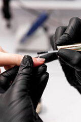 the manicurist applies the coating to the client's nail