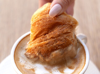 tasty delicious croissants and coffee cappuccino cup with hearts from milk foam in cafe, french pastry.woman hand girl dipping croissant in cup.good morning concept, cozy warm photo