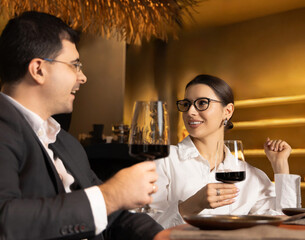 beautiful business woman having lunch in restaurant together with colleagues. man talking to female. girl is eating soup with spoon.smiling lady wearing eyeglasses.team drinking wine.